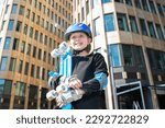 portrait of happy schoolboy in purple helmet, holding blue urban cruiser, skateboard.