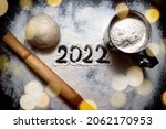 Small photo of Baking flour and number 2022 on blackboard. Top view. rolling pin, flour and shape new year.New year ornament food background. Home made.