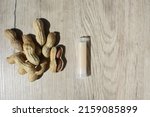 Small photo of Natural lip balms with peanut on wooden background. Lip balm or lip salve. The concept of an unnamed lipstick bottle.Commercial idea concept: Lip balm or salve and peanuts