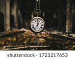 Vintage silver watch with chainlet hanging over the ruins of the cathedral. The wind of time concept.