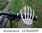 A skeleton's hand on a bicycle handlebar. Danger of careless driving