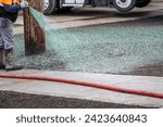 Small photo of Professional hydroseeding, workman spraying a mix of grass seed and wood pulp from a big hose onto a freshly prepared dirt in a new residential community