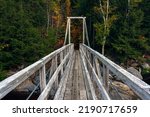 Hiking trail crosses the Ammonoosuc River via a wooden ppedestrian bridge in the White Mountains of New Hampshire.