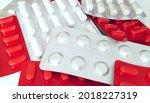 Small photo of A stack of pill blisters. White and red medicine blisters. Unpacked drugs close up. Complex therapy, polypharmacy, pharmacotherapy. Drug policy. Pharmaceutical industry concept.