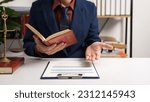 Small photo of Male lawyer working with law book, A legal binding, Unilateral contract, Multilateral, Non-reciprocal contract, Default, Obligation, Power of attorney, Defense of a prescription, Court decree