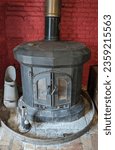 Small photo of Norwich, England 4th September 2023 - antique cast iron wood burning stove set on flagstones in front of a red brick wall - coal scuttle to the right and fireplace brush on stand
