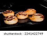 Five baked cinnamon buns on tray in electric oven. Swedish cuisine, homemade bakery, food, cooking and pastry concept
