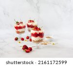 Small photo of Berry dessert in glass with fresh strawberry, biscuit and whipped cream. Vegan lactose free dessert with alternative milk of coconut. Recipe of healthy organic dessert, cheesecake or berry trifle cake