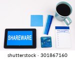 Small photo of Business Term / Business Phrase on Tablet PC - Blues, cup of coffee, Pens, paper clips Calculator with a blue note pad on a White Background - White Word(s) on a blue background - Shareware