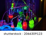 Mad scientist chemistry lab in dark with glowing green and red chemicals