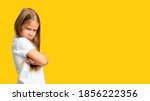 Small photo of Naughty child. Disobedience problem. Discipline punishment. Portrait of angry offended little girl in white with crossed arms isolated on yellow copy space background.