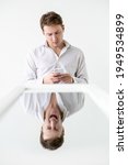 Small photo of Bipolar man. Psychology suppression. Personality stress. Conceptual art portrait. Inversion illusion. Business guy using mobile phone with screaming emotional reflection in mirror isolated white.
