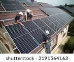 Small photo of Men installers mounting photovoltaic solar moduls on roof of house. Engineers in helmets installing solar panel system outdoors. Concept of alternative and renewable energy. Aerial view.