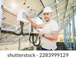 Small photo of Man adjusting electric switchboard according to instuctions. Male worker checking if switchers turned on. Man in helmet turning on switcher on back side of solar system.
