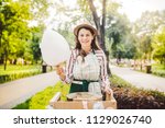 photo theme small business cooking sweets. A young caucasian woman with an apron trader in the hat the owner of the outlet makes a candy floss, a fairy floss or a cotton candy in the summer park.