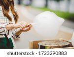 Theme is a family small business cooking sweets. Hands close-up Young woman trader owner of the outlet makes a candy floss, fairy floss or Cotton candy in the park in summer.