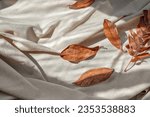 Small photo of Autumn fall leaves and natural sunlight shadows on messy crumpled linen cloth background. Aesthetic autumn flat lay, business brand template.