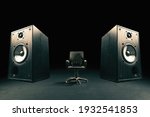 Two sound speakers with office chair between them on black background.