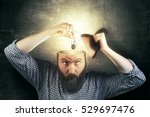 A new idea concept. Image bearded man twists a light bulb in his head as a metaphor of a new idea. Eureka!