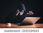 Small photo of Black hat hacker in hood using laptop computer and call smartphone to victim on desk hacking privacy sensitive data hack in dark room background. Cyber security cyber crime concept. Hacking phishing