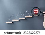 Unlock potential of business success stairs dart and dartboard targets magnifying glass with hand on gray background. Explore opportunities growth embrace steps to achieve ambitions and goal concept.