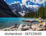 Rocky Mountain view at Moraine Lake in Banff National Park. Blue glacial water and fir trees with canoes.  