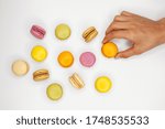 Top view of macaroons colored cookies and a hand that holding one 