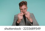 Small photo of Greedy avaricious young business man showing fig negative gesture, you dont get it anyway. Rapacious, avaricious, acquisitive. Body language. Refusal fig sign. Bearded guy on isolated blue background