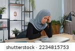 Small photo of Young muslim business woman in hijab headscarf use smartphone typing browsing, loses becoming surprised sudden lottery results, bad news, fortune loss, fail. Girl in modern home office workspace