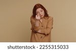 Small photo of Angry aggressive redhead woman showing fig negative gesture, you dont get it anyway. Rapacious, avaricious, acquisitive. Body language. Refusal fig sign. Greedy avaricious girl on beige background