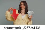 Small photo of Upset pretty woman showing red arrow pointing down, concept of downgrade, unsuccessful business, fall of stock market money dollar exchange rate bankruptcy fail. Young adult girl on gray background