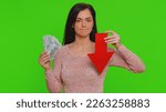Small photo of Upset pretty woman showing red arrow pointing down, concept of downgrade, unsuccessful business, fall of stock market money dollar exchange rate bankruptcy fail. Young girl on chroma key background