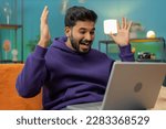 Small photo of Oh my God Wow. Surprised indian man using laptop computer, receive good news message, shocked by sudden victory, celebrate lottery jackpot win purchases online shopping at home. Lifestyle technologies