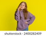 Small photo of Disinterested preteen child girl kid having annoyed boring talk on smartphone. Children tired sleepy freelancer talking on mobile phone with friend, making online conversation on yellow background