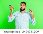 Small photo of Disinterested Indian man having annoyed boring talk on smartphone. Arabian guy tired sleepy freelancer talking on mobile phone with friend, making online conversation on green chroma key background