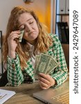 Small photo of Caucasian young woman freelancer counting cash insufficient amount of money. Financial crisis. Bankruptcy. Poverty and destitution. Female girl businesswoman with laptop sitting at home office desk