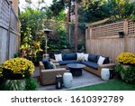 Patio. Garden. Urban, neutral, outdoor living space. Exterior photo. Outdoor living room with couch, comfy cushions, throw pillows, love seat, chairs and coffee table. Backyard with greenery, plants.