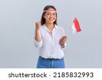 Excited young Asian woman celebrate Indonesian independence day holding the Indonesian flag isolated on white background