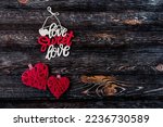 Concept for Valentine's Day. Inscription love sweet love. Two red woven hearts of love on a dark wooden background.