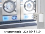 Small photo of White plug on white wall with a lot of washing machine in a public laundromat in the background, plug socket, plug electric, plug outlet, backdrop. White outlet interior.