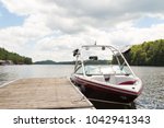 A wakeboard boat at a wooden dock in the Muskokas on a sunny day. 