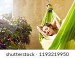 happy young woman relaxed lies in a hammock on the balcony House. Woman basks and sunbathes in a hammock