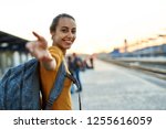 portrait of a young woman traveler with small backpack on the railway stantion. woman waiting for train. Follow me, active and travel lifestyle concept.