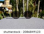 Sunglasses with black frames and photochromic lenses on a rock and urban background, perfect for editorial or commercial use