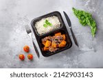 Small photo of a dish in a black disposable container from catering on a concrete background, dietary catering, ready meals with you, healthy food