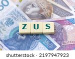 Small photo of Shortcut of polish social security office written in polish with blocks standing on polish banknotes, "zus" means Social Security. Close up.