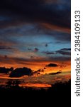 Small photo of Beautiful sky on twilight time. Cloudy rose blue sunset over dark silhouettes of trees in nature. Real amazing panoramic sunrise or sunset sky with hot-tempered and vehement clouds.