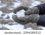 Small photo of People playing snowballs.Girl in warm knitted mittens holding a snowball.Winter entertainment.
