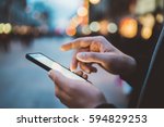 Close-up image of male hands using smartphone at night on city shopping street, searching or social networks concept, hipster man typing an sms message to his friends