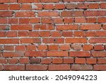 Small photo of Photo of the texture of a brick wall, made of red clay bricks with inflows of cement mortar and uneven brickwork.